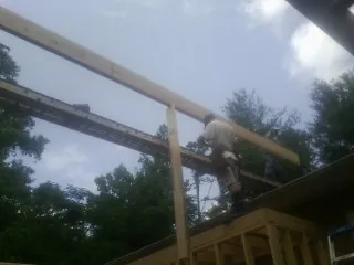 Carpenter setting a ridge beam over a new addition frame — Ice Dam Removal by Roofing Brothers in Mc Leod