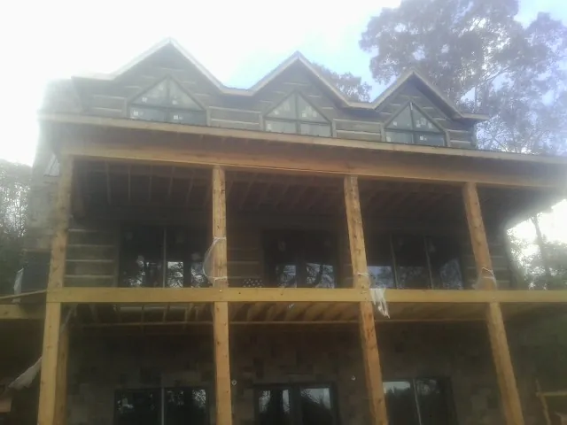 Dormers and porch framing on a large log home under construction — Roof Coating work by our crew in Mc Leod