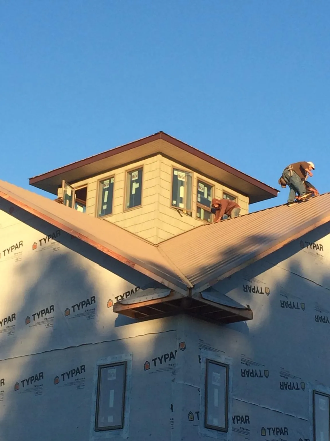 Roofers working around a rooftop cupola on a new metal roof at sunset — Roof Waterproofing in Mc Leod by Roofing Brothers